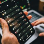 Person holding smartphone showing cryptocurrency market data, symbolizing digital investment tools.